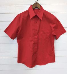 Women's size 14 bright red vintage button down top 20" chest (measured armpit to armpit) 21" hips 25.5" length (measured shoulder to bottom seam) 6.5" sleeve opening 3.5" sleeve length Estimated 1980s vintage blouse with button down closure and structured collar One functional pocket on chest 65% polyester, 35% cotton In pristine condition- no rips, fraying, discoloration, stains or holes! *The Pearl Vintage Shop Disclaimer* Please note: This is a previously-used vintage clothing item. Be aware that the item may not be in perfect condition and may show signs of wear. All noticeable flaws will be described in the item description as well as included in the photos. The buyer is responsible for shipping fees on all returns. Fitted Solid Color Blouse, Classic Solid Tops With Button Closure, Classic Fitted Plain Blouse, Red Collared Shirt With Buttons, Classic Collared Blouse, Classic Collared Plain Blouse, Classic Fitted Plain Shirt, Fitted Classic Plain Shirt, Fitted Plain Office Top