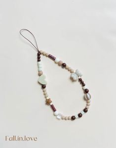 a beaded necklace with white and brown beads on a white background, that says i all in love