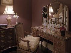 a desk with a chair, mirror and lamp in a room that has purple walls