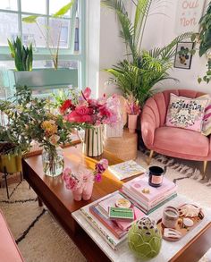 a living room filled with pink furniture and lots of plants on top of the coffee table