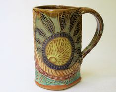 a ceramic coffee mug with an artistic design on it's side, sitting on a white surface