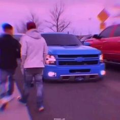 two men walking down the street in front of some cars