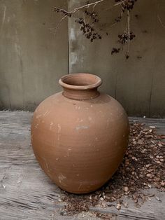 a large brown vase sitting on top of a wooden floor next to a tree branch