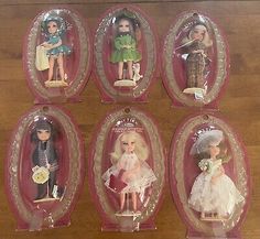 six dolls in plastic cases on a wooden table