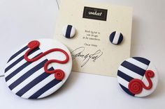 a pair of blue and white striped earrings with red swirls on the ear wires