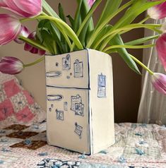 a vase filled with pink tulips on top of a bed next to a window