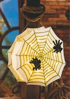 a spider web light hanging from a wooden pole