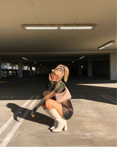 a woman kneeling down in the middle of a parking lot with her hand on her hip