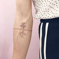 a woman's arm with a small tree tattoo on the left side of her arm