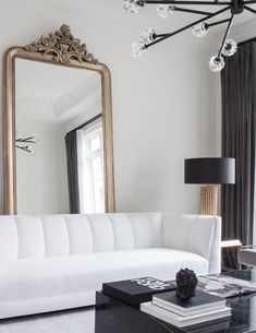 a living room with a white couch and a large mirror on the wall above it