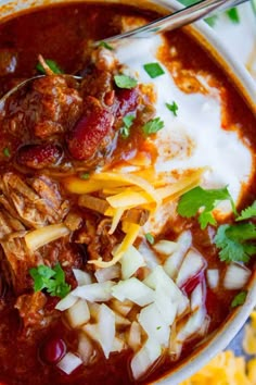 a bowl filled with chili and cheese next to tortilla chips