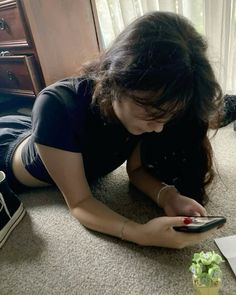 a woman laying on the floor looking at her cell phone