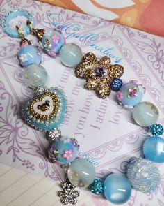 a close up of a bracelet with beads and charms on top of a piece of paper