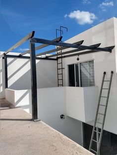 a ladder is attached to the side of a white building with windows and shutters