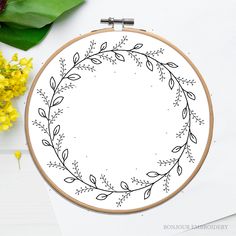 a cross stitch pattern with leaves and flowers in the hoop on a white table next to yellow flowers