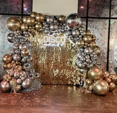 a gold and silver christmas display with ornaments on the floor in front of a wall