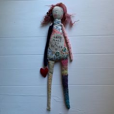 a doll hanging from the side of a wall with words on it and a heart