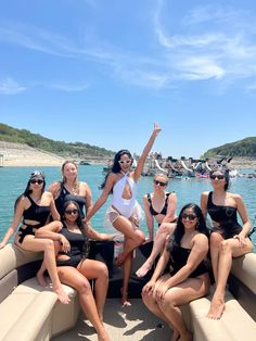 a group of women sitting on the back of a boat posing for a photo with their arms in the air