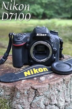 a nikon d700 camera sitting on top of a tree stump