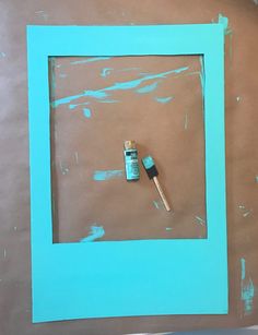 a blue frame with some paint on it and a brush next to it in the middle