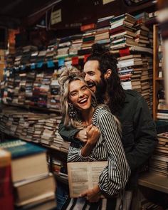 a man and woman standing next to each other in front of books