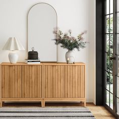 a room with a dresser, mirror and vase on the floor next to a door