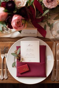 a place setting with red napkins, silverware and pink flowers on the table