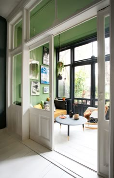 an open door leading to a living room with green walls and white flooring on the outside