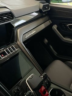 the interior of a car with black leather and red trims, including an electronic display