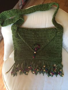 a green crocheted purse sitting on top of a white chair