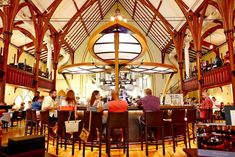 people are sitting at tables in the middle of a large room with high vaulted ceilings