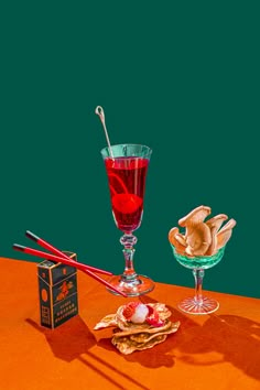 an orange table topped with two glasses filled with liquid and other items on top of it