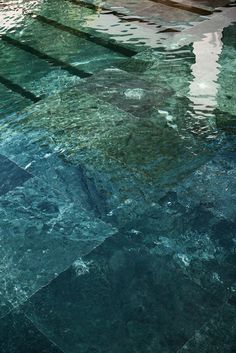 an empty swimming pool with tiled floors and blue water