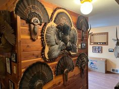 a deer head mounted to the side of a wooden wall with turkey heads on it