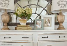 a white dresser topped with lots of drawers covered in pictures and vases filled with flowers