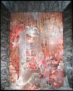 a window display with pink and white decorations on it's sides, in front of a curtained wall