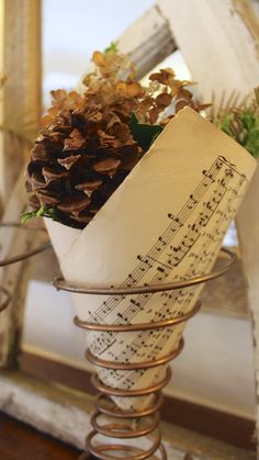 a white vase filled with pine cones and music notes