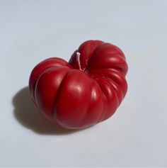 a red tomato sitting on top of a white table