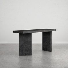 a black table sitting on top of a cement floor next to a white wall in an empty room