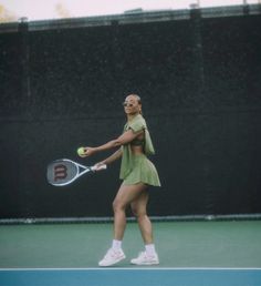 a woman holding a tennis racquet on top of a tennis court with a ball in her hand