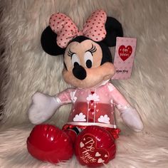 a minnie mouse stuffed animal sitting on top of a white fur covered bed next to two boxing gloves