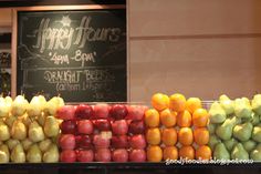 apples, oranges and pears are displayed in front of a happy hours sign