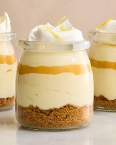 three glass jars filled with dessert sitting on top of a table