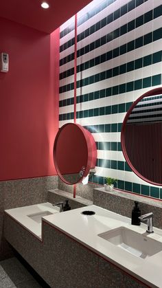 a bathroom with two sinks and mirrors in the middle of it, one is red