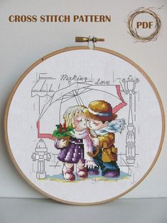 the cross stitch pattern shows two children kissing under an umbrella, while holding hands and looking at each other