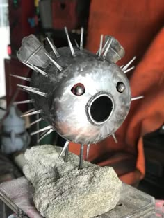 a metal object with spikes sticking out of it's face sitting on top of a rock