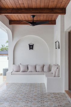 a white couch sitting under a wooden ceiling next to a wall with windows and doors