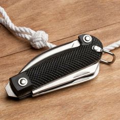 a black and silver pocket knife sitting on top of a wooden table next to a rope