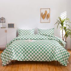 a green and white checkered comforter set on a bed in a room with wooden floors