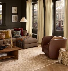 a living room filled with lots of furniture next to two large windows covered in curtains